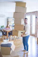 Poster - Young couple moving to a new house, man holding cardboard boxes worried about falling for overweight