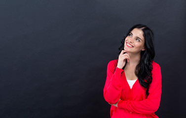 Young woman in a thoughtful pose on a black background