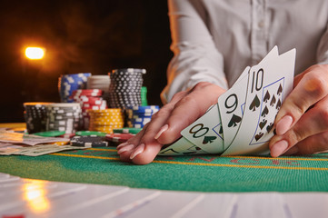 croupier raises a combination of street poker cards in a casino, poker table, chips, dollars. background for a casino gaming business