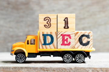 Wall Mural - Truck hold letter block in word 31dec on wood background (Concept for date 31 month December)