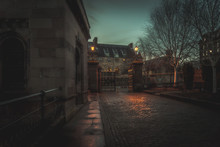 GLASGOW, SCOTLAND, DECEMBER 16, 2018: Creepy Cobbled Street Surrounded By Old European Style Buildings. Illuminated Only With Weak Light From Street Lamps.