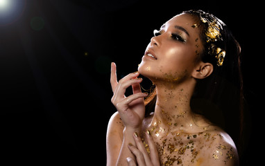 Fashion Young Asian Woman eyes brown black straight hair beautiful make up fashion decorate with Golden Foil or Gold leaf all over neck and shoulder. Studio Lighting dark Background star holes smoke