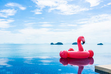 Beautiful Outdoor Swimming Pool In Hotel Resort With Flamingo Float Around Sea Ocean White Cloud On Blue Sky