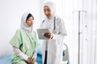 © Art_Photo - Muslim asian female doctor consulting and check up information on tablet computer with muslim woman in hospital.woman has sick.healthcare and medicine