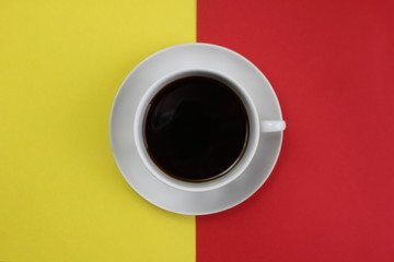 a cup with a coffee stands on a red and yellow background at the same time