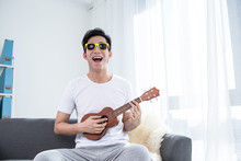 LWTWL0008335 Portrait Of Young Relaxed Man Play The Ukulele