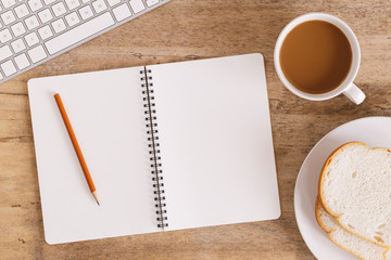 Wall Mural - top view of the office table on the table there are notebook, coffee cup, bread, pencil and keyboard