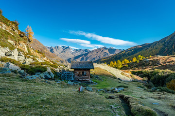 Wooden hut at hiking path at Timmelsjoch and Texelgruppe nature park leading to the Seebersee with the alpine mountains in the background