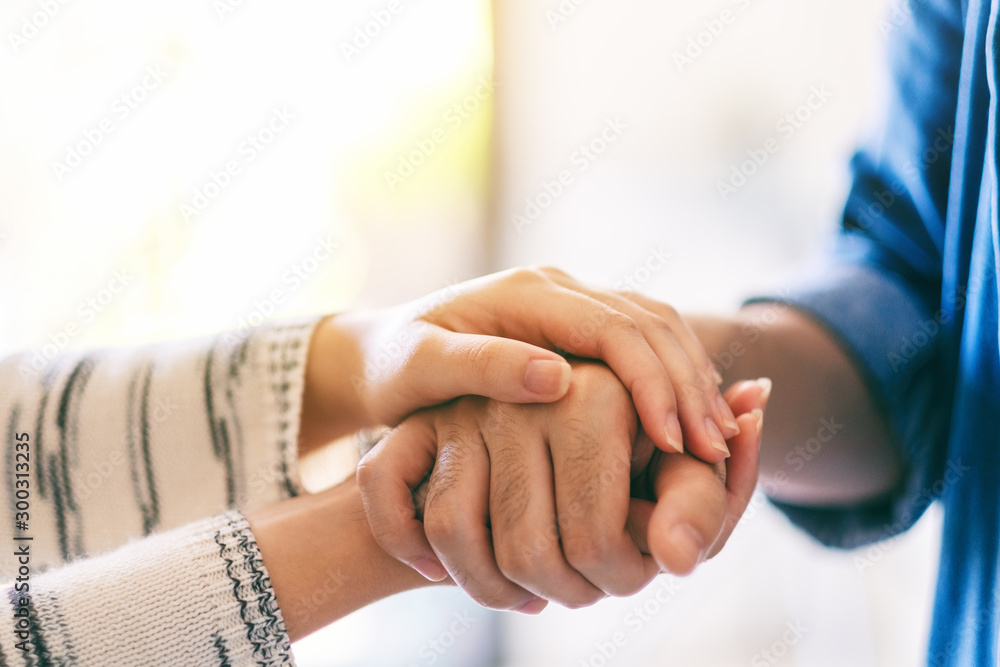 A man and a woman holding each other hands for comfort and sympathy - obrazy, fototapety, plakaty 