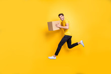 Full Size Photo Of Handsome Guy Jumping High Holding Parcel Box Hurry Move New Apartments Transportation Wear Casual T-shirt Pants Isolated Yellow Color Background