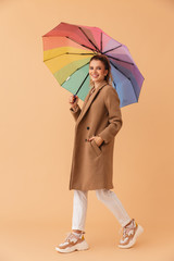 Poster - Photo of happy nice woman holding multicolor umbrella while walking