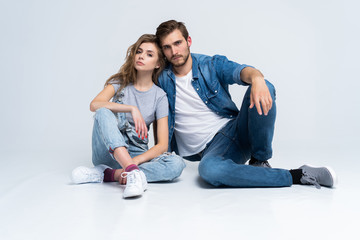 Wall Mural - Portrait Of Happy Young Couple Sitting On Floor Leaning Against Wall