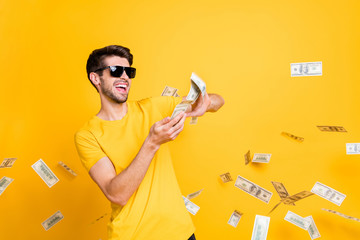 Portrait of his he nice attractive glad cheerful cheery guy throwing away large sum of money budget finance freedom isolated over bright vivid shine vibrant yellow color background