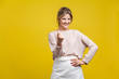Come here! Portrait of playful happy young woman with fair hair in casual beige blouse standing, calling with finger gesture, inviting to come in. indoor studio shot isolated on yellow background