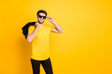 Photo of handsome guy holding boutique bags making abroad shopping self-confident classy person wear casual t-shirt pants isolated yellow color background