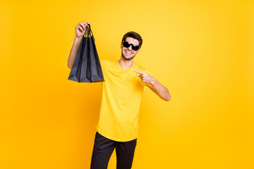 Portrait of his he nice attractive fashionable cheerful cheery guy demonstrating bags new clothing things good choice isolated over bright vivid shine vibrant yellow color background