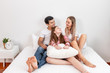 © wirojsid - Happy family, including father mother and daughter, are sitting on bed with smile, looking at each other