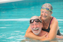 Couple Of Two Seniors Hugged In The Water Of Swimming Pool - Active Man And Woman Doing Exercise Together At The Pool - Hugged With Love
