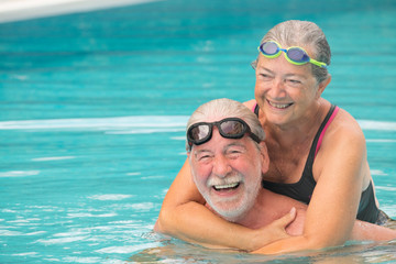 Sticker - couple of two seniors hugged in the water of swimming pool - active man and woman doing exercise together at the pool - hugged with love