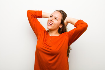 Wall Mural - young woman smiling and feeling relaxed, satisfied and carefree, laughing positively and chilling against white background