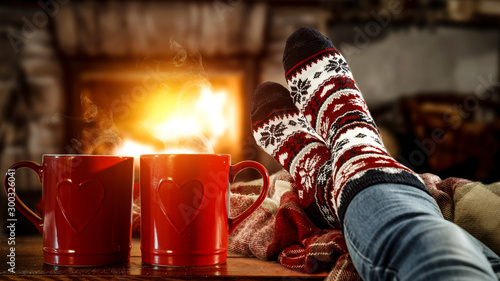 Cuadros en Lienzo Woman legs with christmas socks and fireplace in home interior.