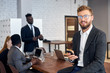 © alfa27 - Cheerful young man in tuxedo and eyeglasses using smartphone in workplace while his business colleagues having conversation in background