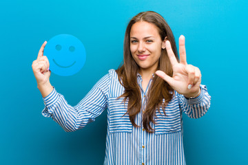 Wall Mural - young woman with a smiley face against blue background