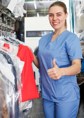 Wall Mural - Glad worker of laundry inspecting clothing