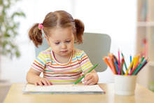 Cute Little Child Girl Writing With Pencils In Day Care Center