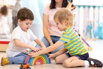 preschool children playing with colorful wooden toys in kindergarten