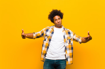 Wall Mural - young black man looking proud, arrogant, happy, surprised and satisfied, pointing to self, feeling like a winner against orange wall