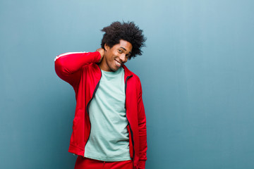 Wall Mural - young black sports man laughing cheerfully and confidently with a casual, happy, friendly smile against grunge wall