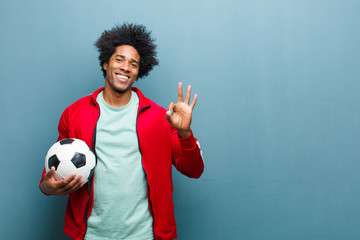 Wall Mural - young black sports man with a soccer ball against blue grunge wa