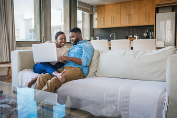 Poster - Smiling African American couple using a laptop together at home