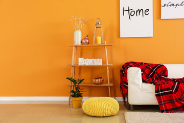 Stylish interior of room with sofa and shelving unit near color wall