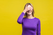 So shameful, I'd rather not watch this! Portrait of bashful positive woman in elegant purple dress covering eyes with hand and laughing, shy to look. indoor studio shot isolated on yellow background