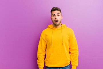 Wall Mural - young hispanic man with casual look against purple background