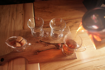 a young man pours tea from a hot teapot into a clear Cup on a wooden table in the evening on dark background