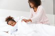 © Drobot Dean - Image of african american woman covering her sleeping daughter with blanket