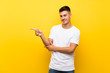 © luismolinero - Young handsome man over isolated yellow background pointing finger to the side