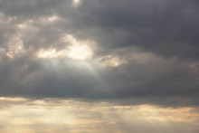 Background Image Of A Dramatic Overcast Sky With Rain Clouds Through Which The Sun Looks Out.
