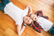 © olezzo - Father and son, 8 years old boy in checkered shirts lie head to head on a wooden floor, top view