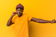 © Asier - Young black man wearing rastas over yellow background dancing and having fun.
