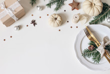 Traditional Christmas Table Place Setting. Golden Cutlery, Porcelain Plate, Fir Tree Branches, Gift Box, Pine Cones And White Pumkins. Christmas Baubles Decoration. Holidays Background. Flat Lay, Top.