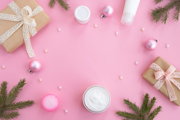 Cosmetic products, gifts boxes and festive decor on a light pink background. Concept of Christmas and New Year gifts, beauty and skin care. Top view, flat lay, copy space