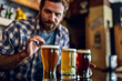 © PhotoAlto - Man looking at beer glass while standing in the bar
