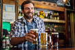 © PhotoAlto - Smiling man serving beer at counter in the bar