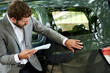 © PhotoAlto - Car salesman with documents examining a car