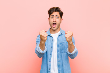 Wall Mural - young handsome man celebrating an unbelievable success like a winner, looking excited and happy saying take that! against pink background