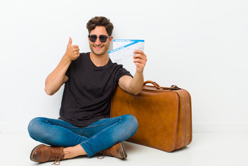 Wall Mural - young handsome man with a boarding pass tickets sitting on the floor in a white room